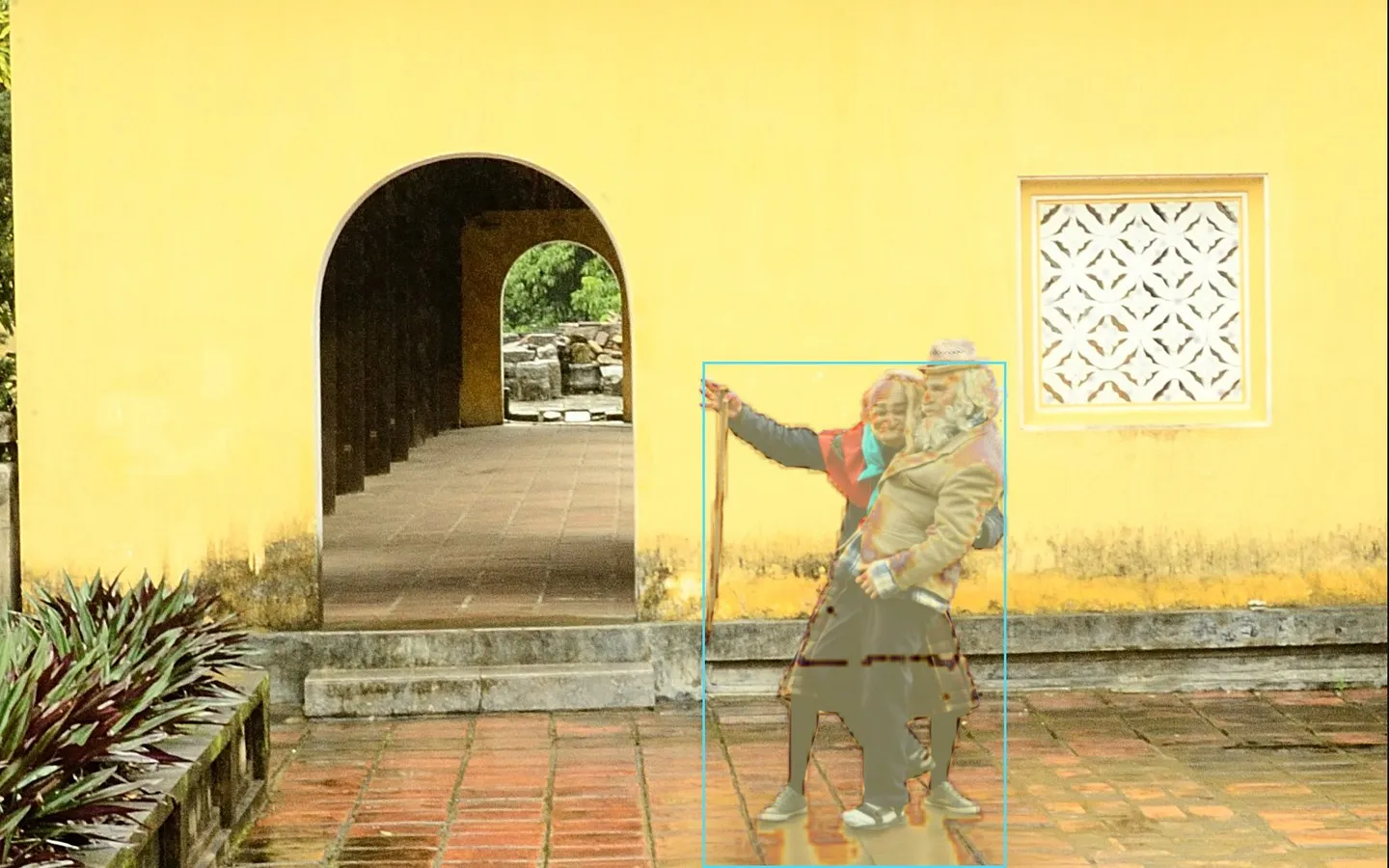 A courtyard photograph with two pasted figures highlighted by the detection heatmap and a bounding box