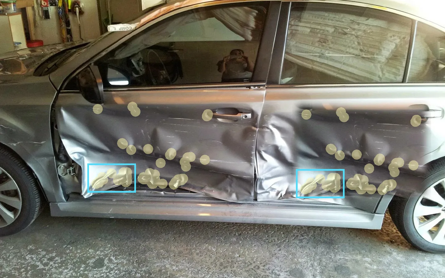 A damaged car photographed for an insurance claim, with the detection heatmap over the bodywork and two boxes marking the same damage found twice